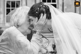 At Courteenhall Estate, the bride and her granny share a touching face-to-face embrace, their expressions radiating warmth and affection, highlighting the deep generational bond and love on this special day.